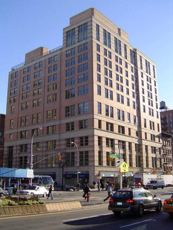 A 12-story stone building at the corner of two streets.