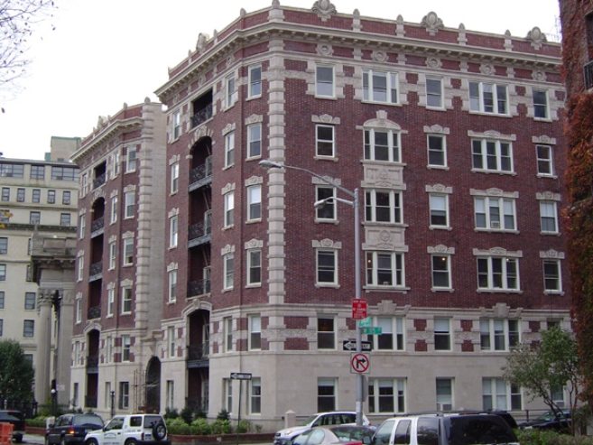 A 6-story red brick building at the corner of two streets.