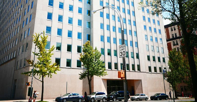 The exterior of Interchurch with trees and cars parked in front of the beige building