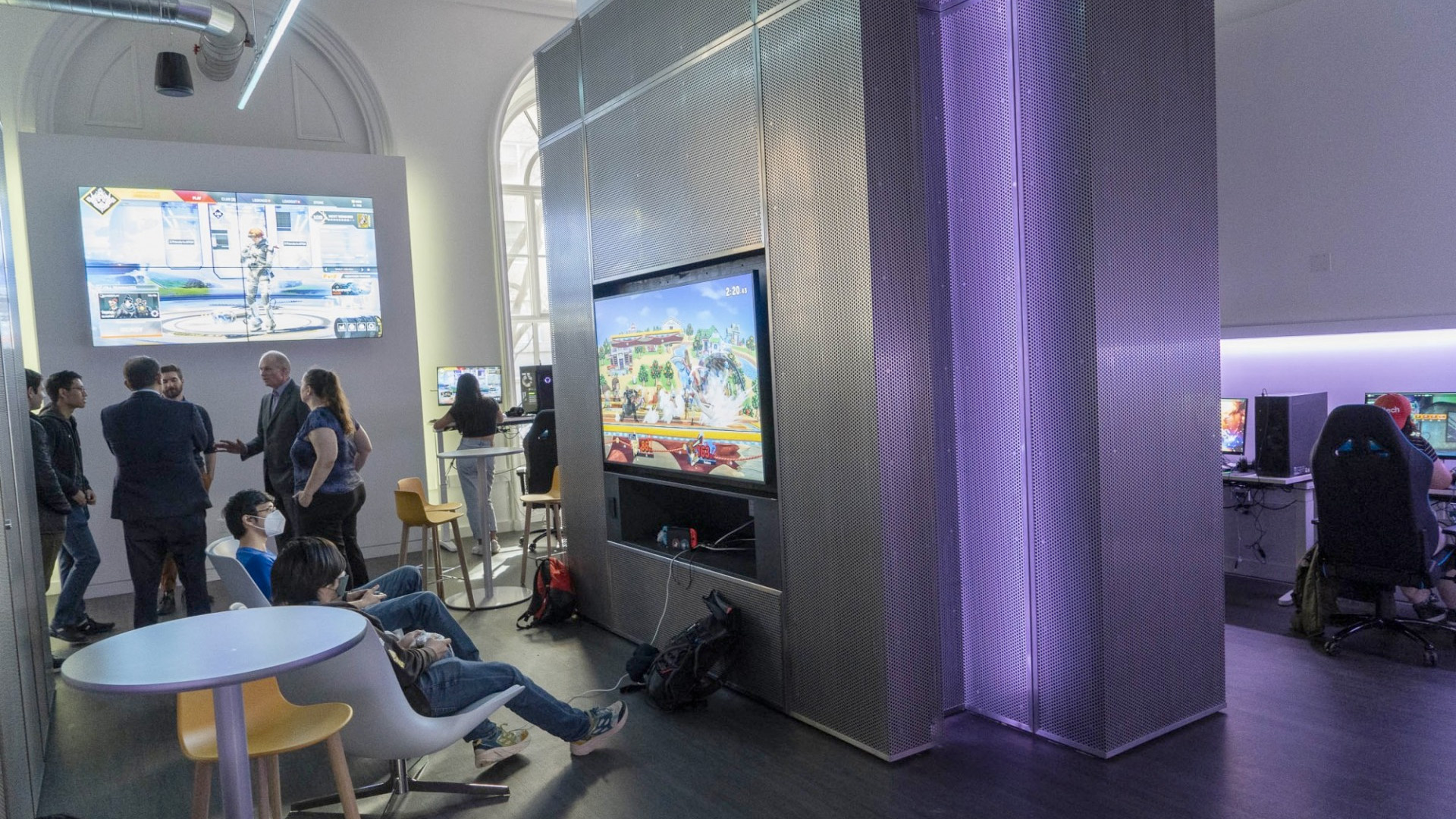 A view of the new Wallach Esports lounge that has students gathered around big screen tvs that are displaying video games.