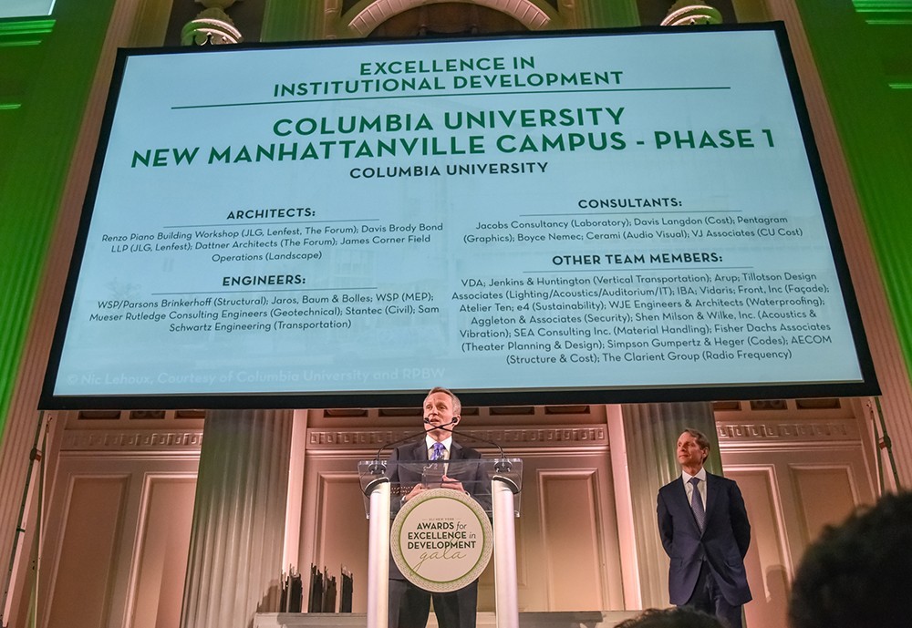 David M. Greenberg, executive vice president for Columbia University Facilities and Operations, accepted the award at the ULI NY gala reception on April 4, 2019. David is standing at a podium on stage wearing a dark suit. Above him is a projector screen displaying the names of architects, engineers, consultants, and other team members who assisted with Phase 1 of Manhattanville campus construction. 