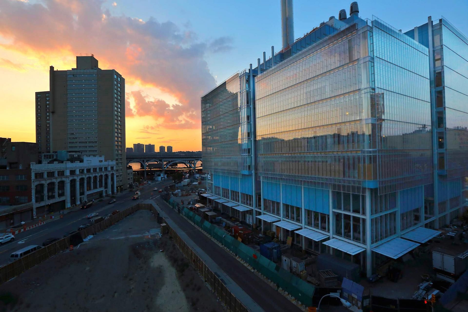 View of Jerome L. Greene Science Center, a glass and steel structure, against a sunset.