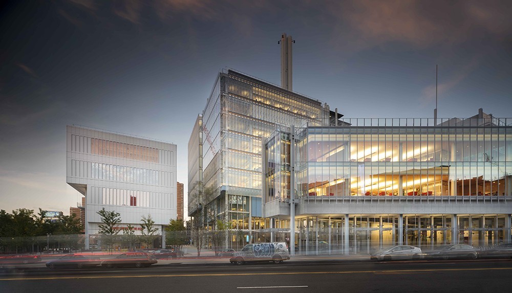 Lenfest Center for the Arts, Jerome L. Greene Science Center, and The Forum at Columbia's Manhattanville campus. The buildings are glass, steel, and concrete structures. In the foreground, there is a street.