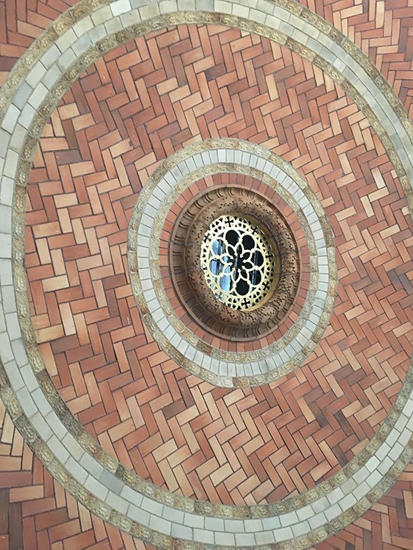 A close-up view of the interior dome ceiling Guastavino tiles. At the center of the tiles is a gold filigree through which sunlight enters the chapel.