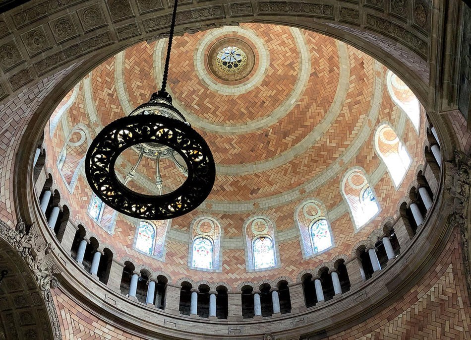 Sixteen stained glass windows encircle the ceiling of the upper dome. Light shines through the windows.