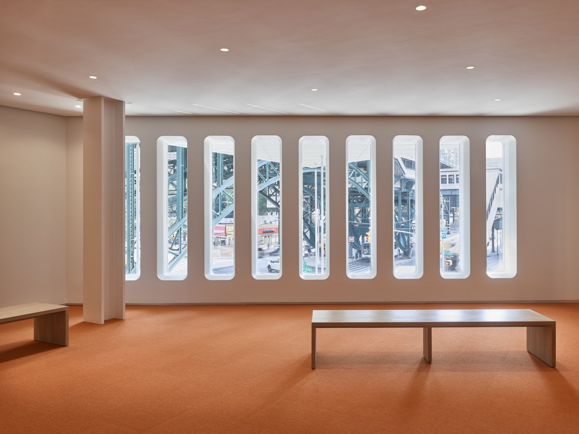 The Forum foyer: A wooden bench faces a cylindrical windows showing a view of West 125th St.