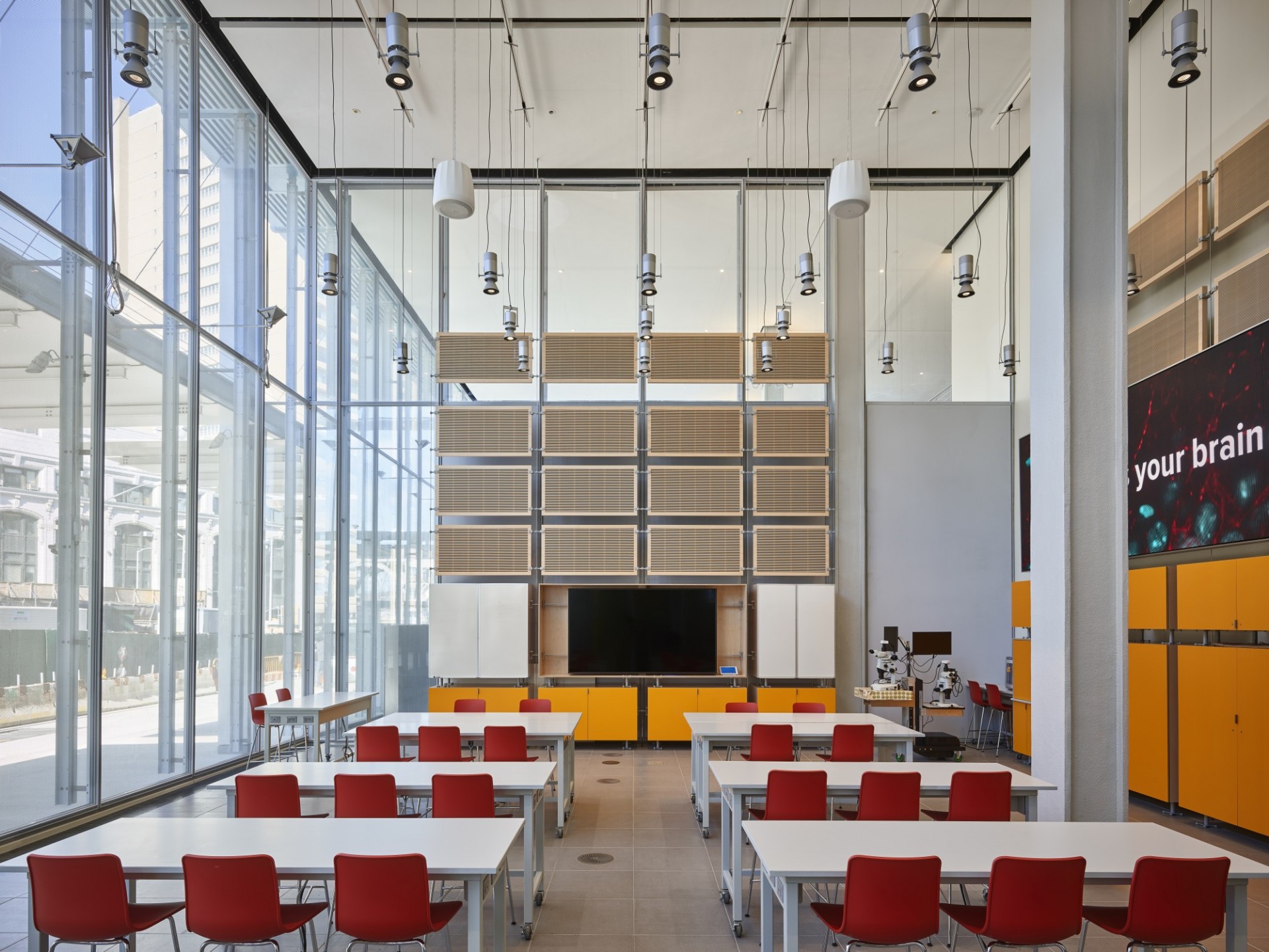 A classroom in the JLG Science Center with rows of red chairs at white, bench-style tables facing a TV monitor.
