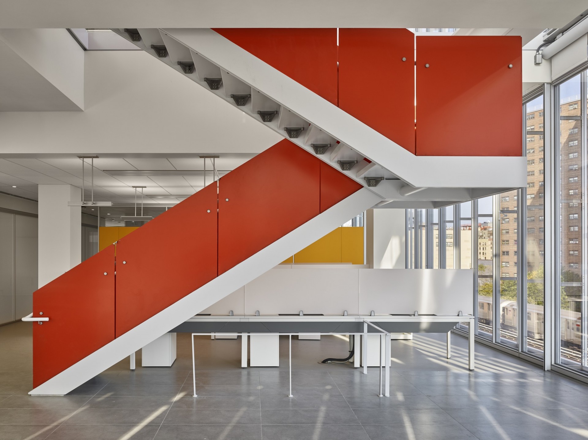 A staircase with red-orange siding bisects an open space work area