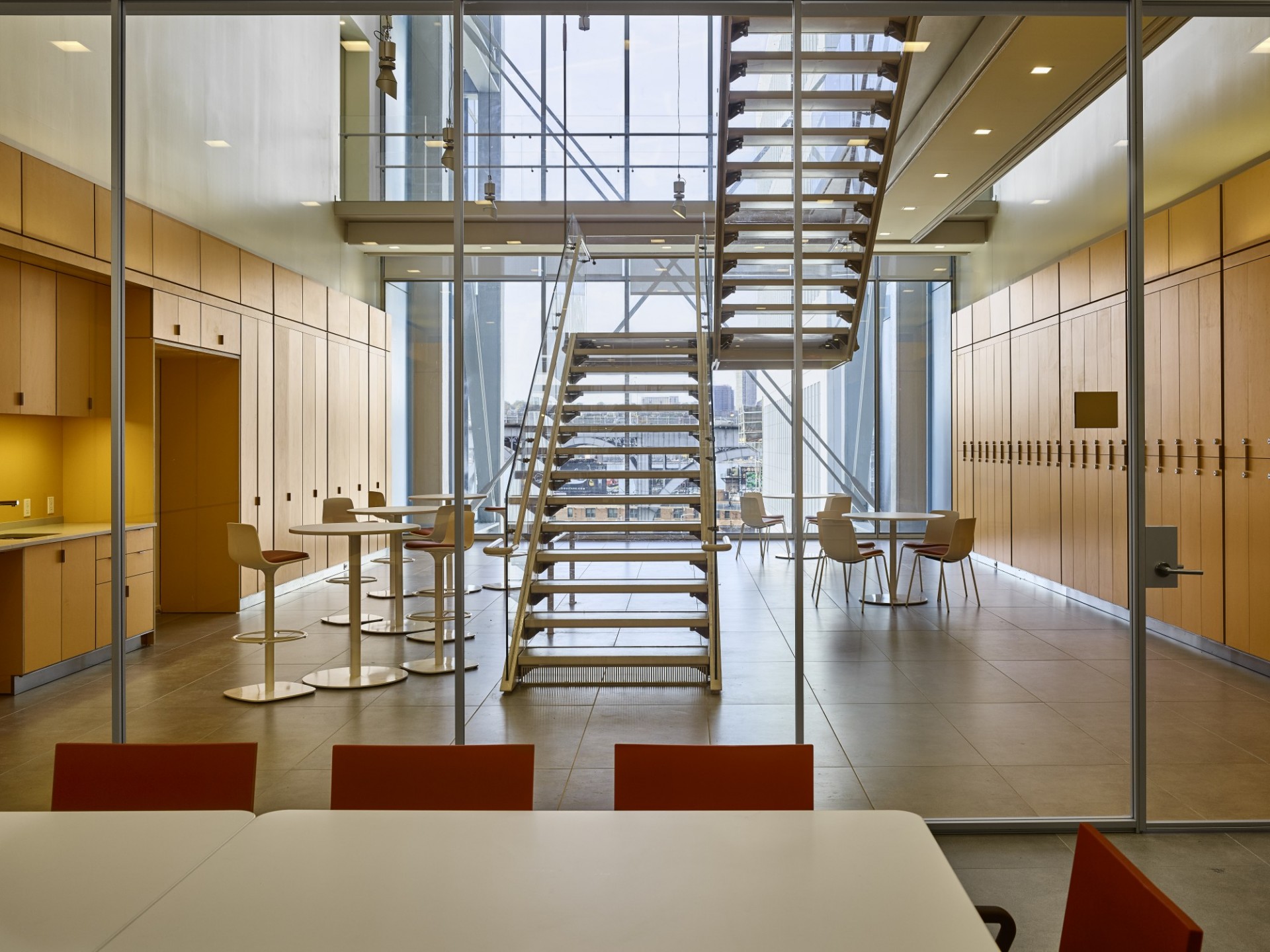A metal staircase bisects a seating area with wooden chairs