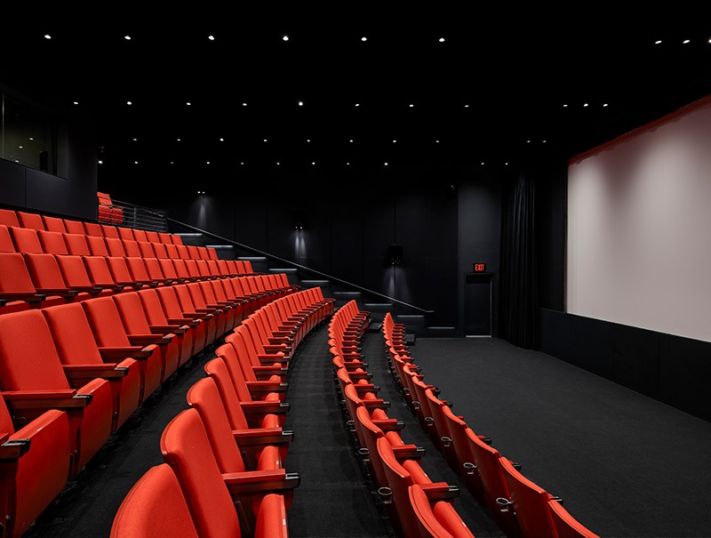 Lenfest Screen Room: Theater-style rows of red-orange chairs facing a large projector screen in a black-walled and -carpeted room.