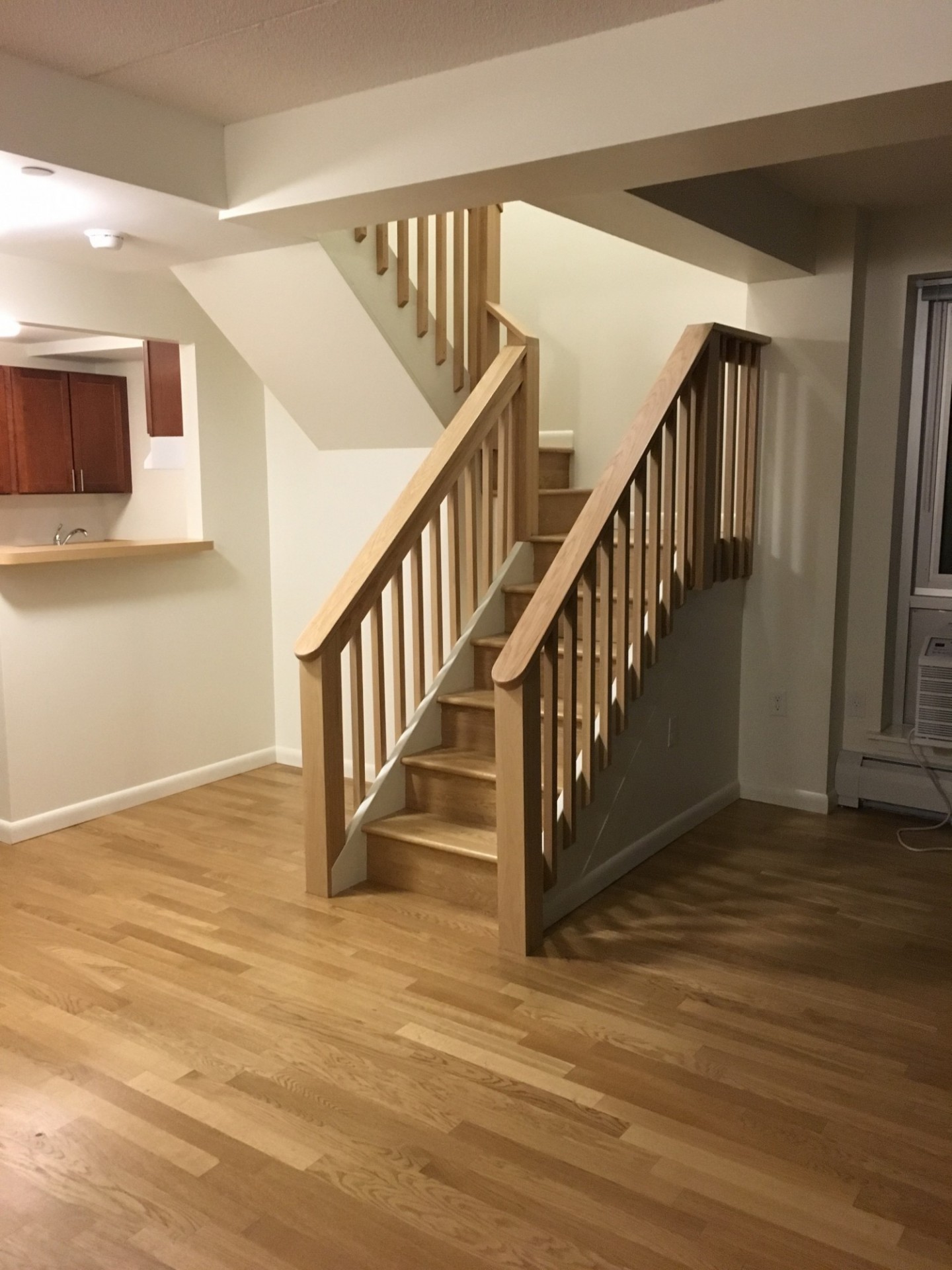The interior of a duplex unit. A wooden staircase in the livingroom of a duplex unit.