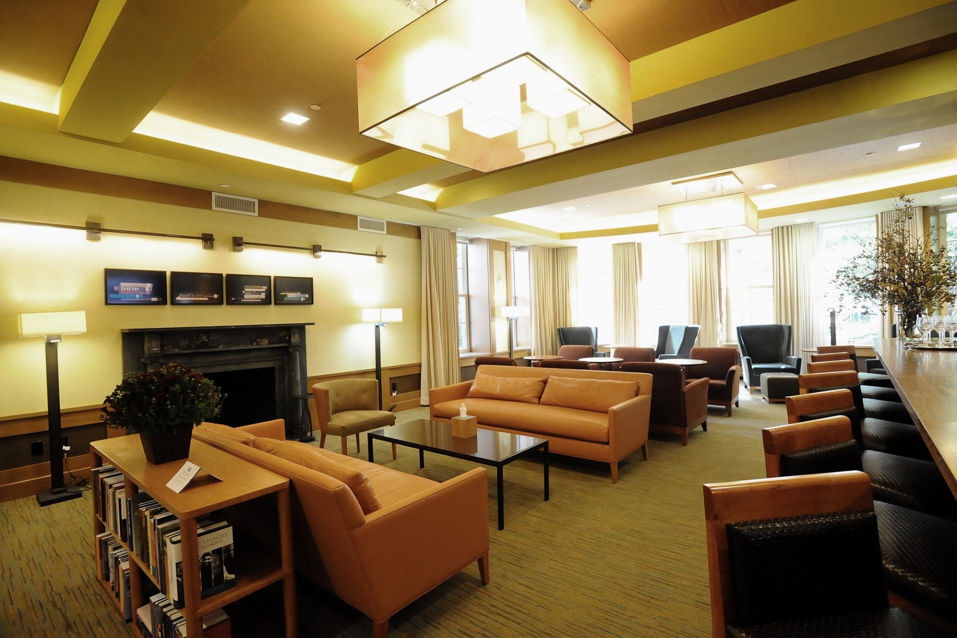 A lounge with neutral colored couches and lounge chairs. The walls are painted white and sunlight streams through windows.