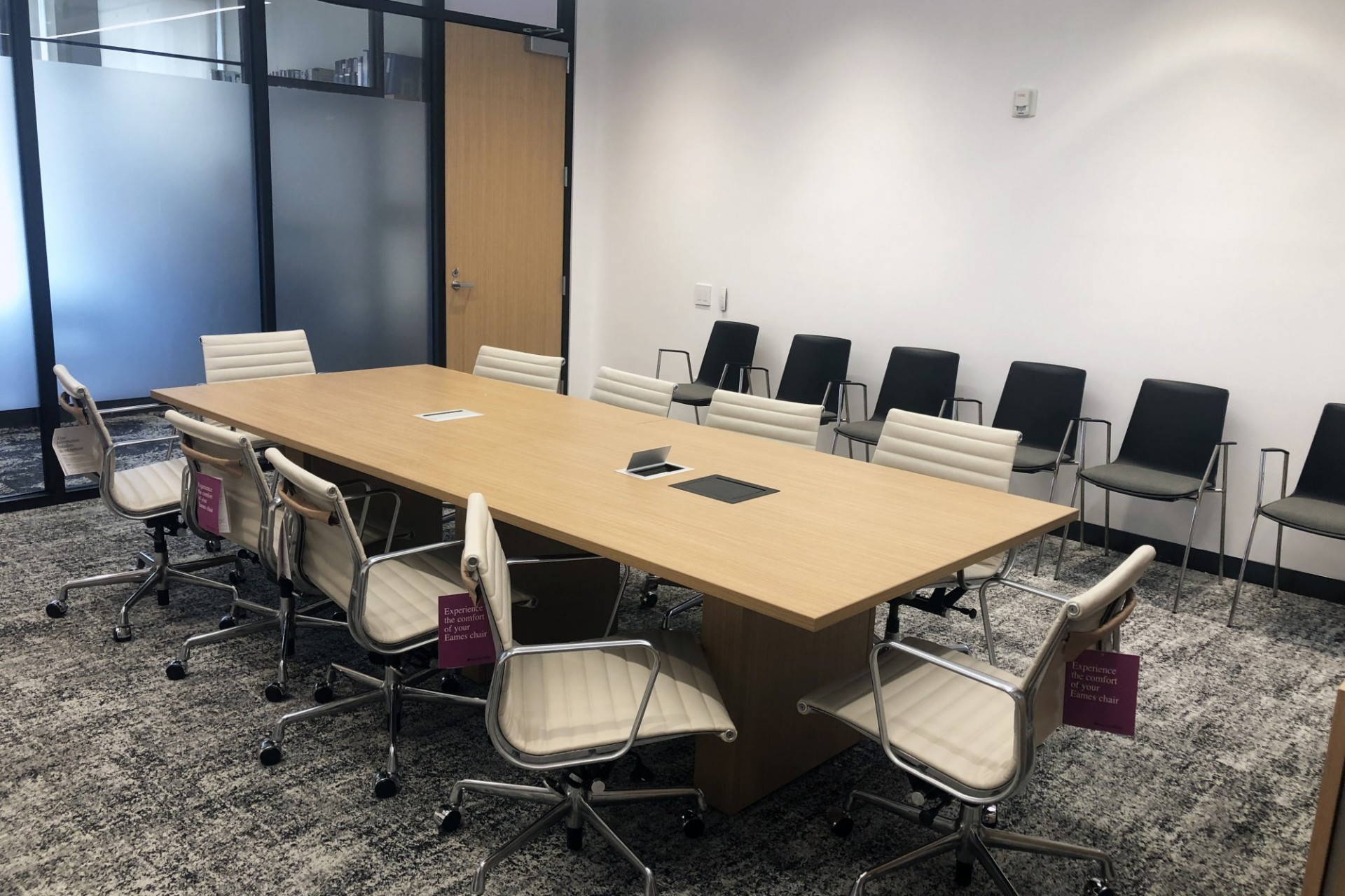 A renovated conference room with new carpeting, a new conference table, and seating around the table and lined up against the wall.