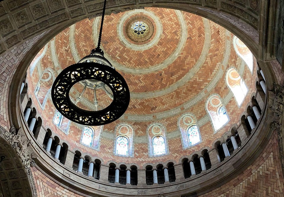 View of the interior dome of St. Paul's Chapel showing Guastavino tiles. Sunshine blasts through the stained glass windows around the top of the dome.