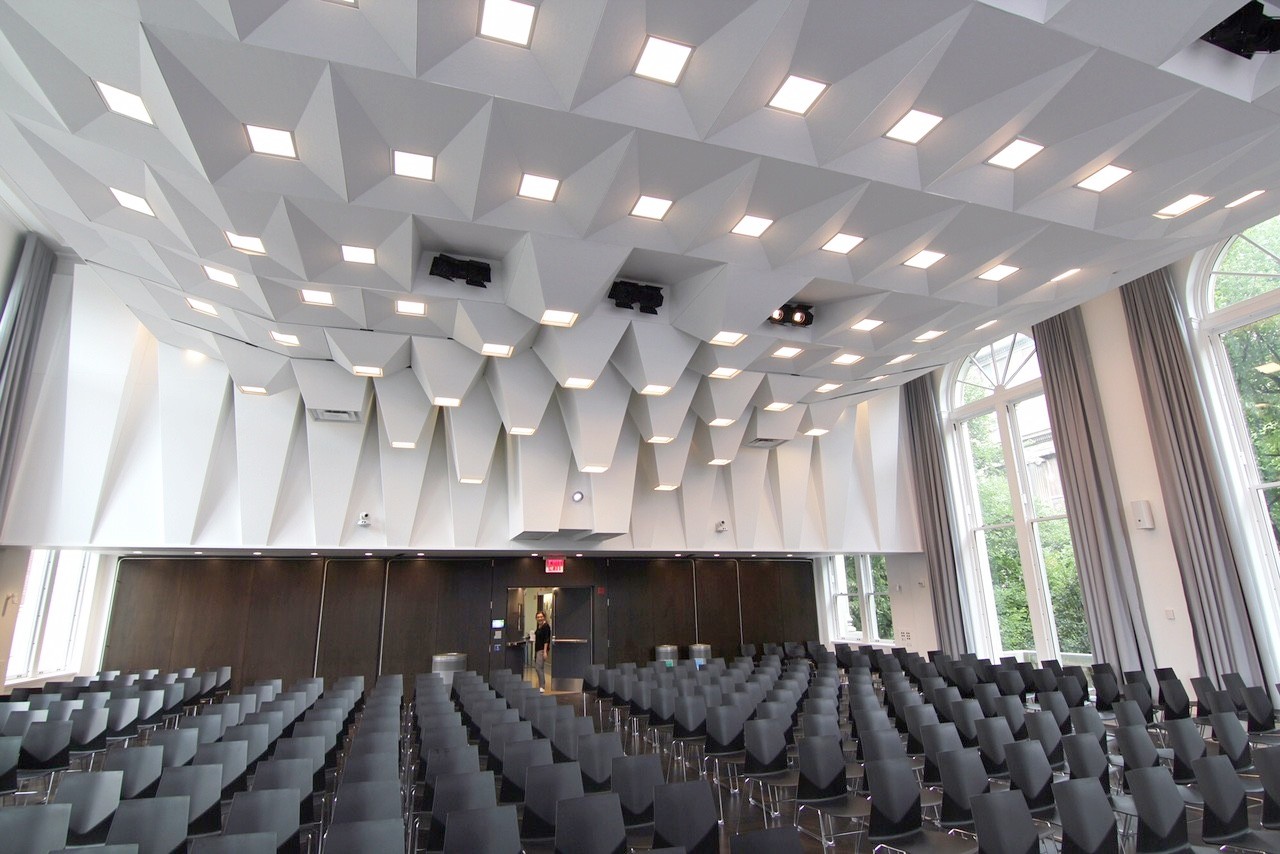 The Jamail Lecture Hall, with a large acoustical ceiling and rows of black chairs lined up on the floor.