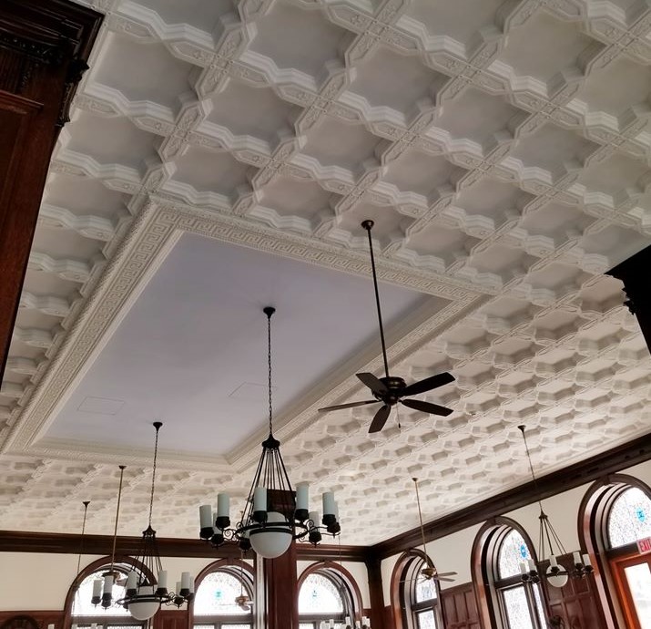 View of white paneled ceiling with hanging fans and chandeliers
