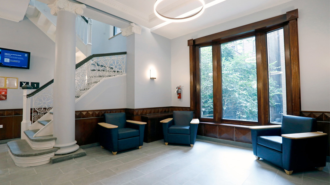 The River Hall lobby with new lighting and flooring, and blue furniture along a large window. 