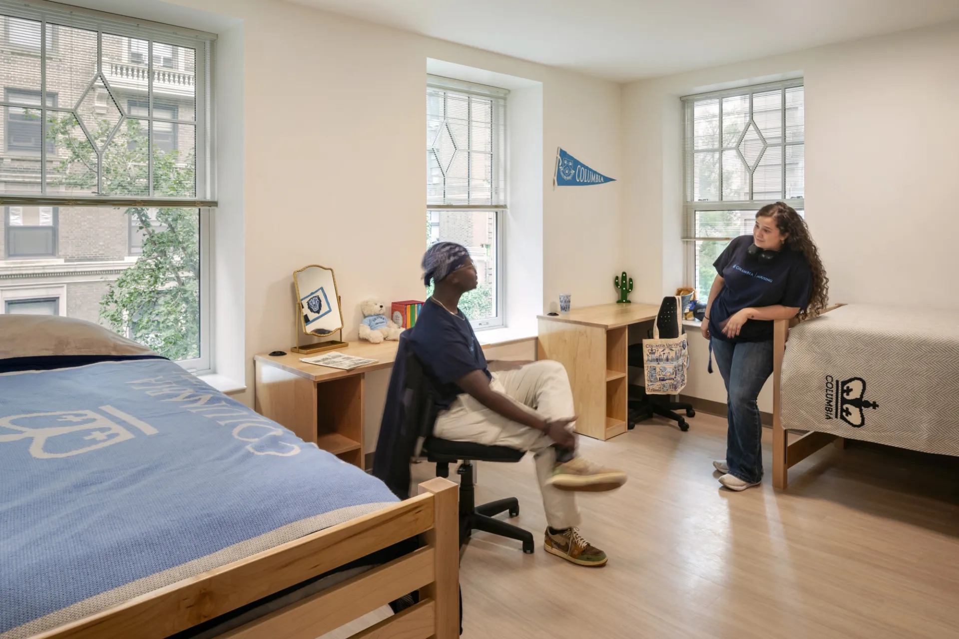 Two students sit in a double room and talk to each other inside a renovated dorm room in 611 W. 112th Street.
