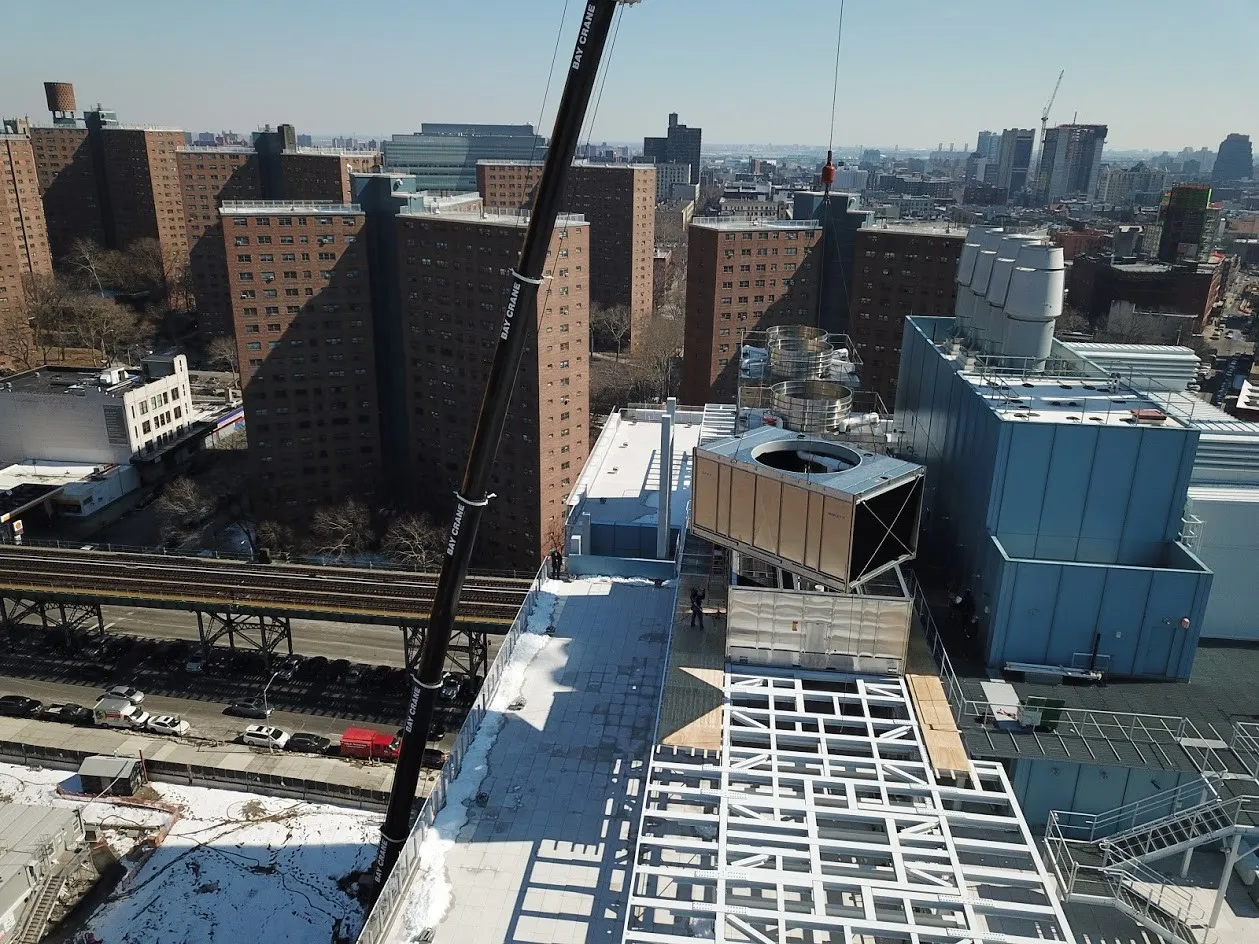 A crane loads metal cooling towers onto the roof of the Jerome L. Green Science Center.