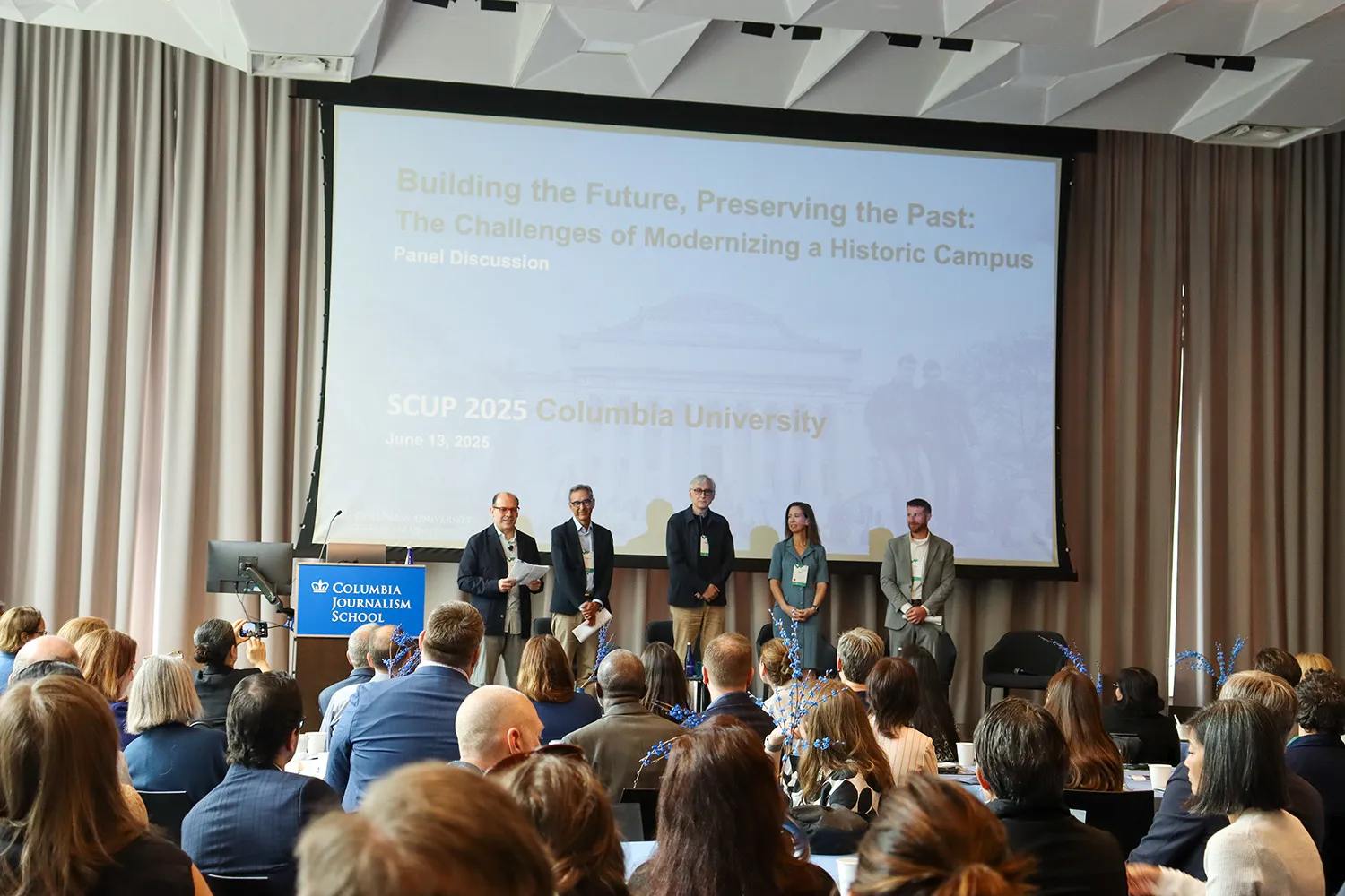 Patrick Saavedra, Assistant Vice President of Capital Project Management; Gene Villalobos, executive director of Facilities Planning and Space Planning Management; Reinhold Martin, professor of architecture from Columbia’s Graduate School of Architecture, Planning and Preservation; Alexis Abramson, dean of Columbia Climate School; and Sean Scollins, assistant vice president of Engineering and Energy Management stand on stage for the first panel discussion at the SCUP 2025 North Atlantic Symposium. 