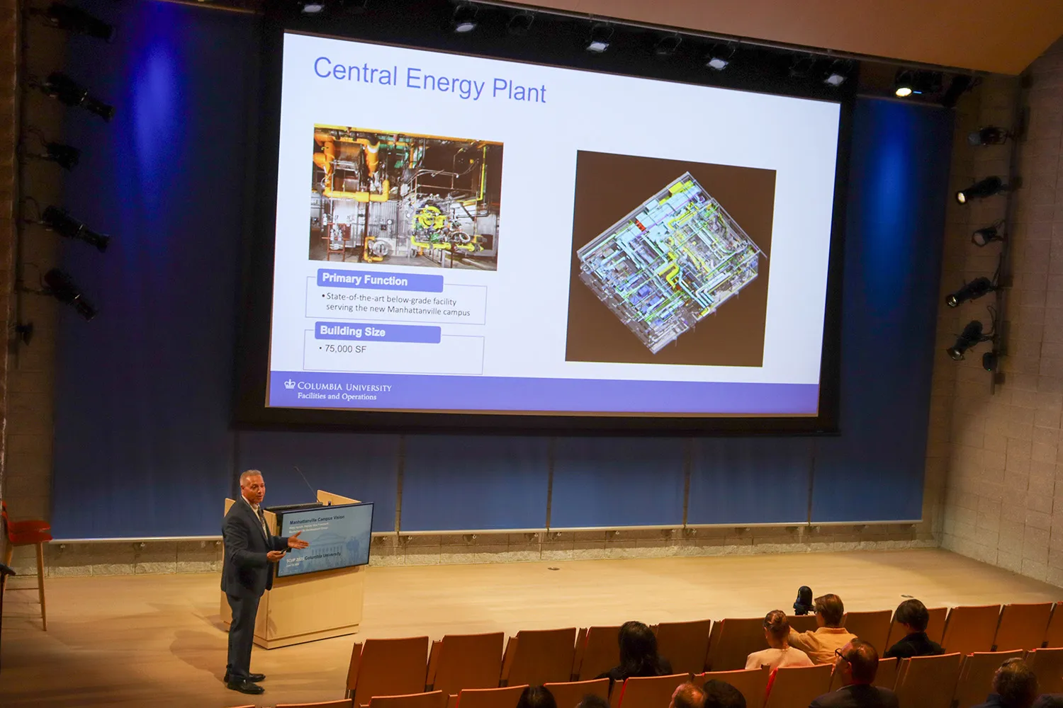 Hany Ayoub, vice president of Manhattanville Development Group, stands in the Lee C. Bollinger Forum auditorium and talks to a slide on the Central Energy Plant.