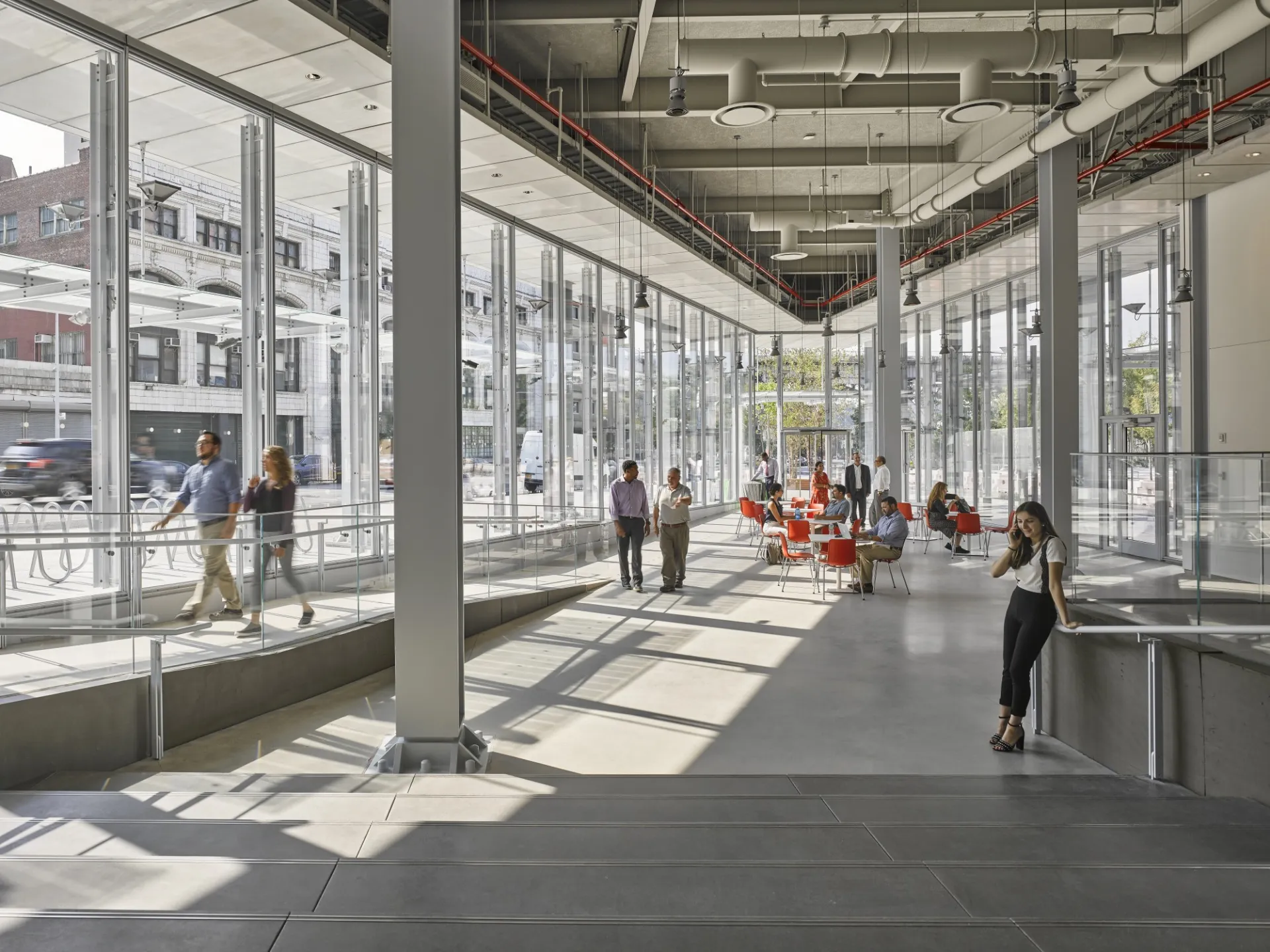 The Forum lobby in use, an industrial-looking spaces with glass windows and high ceilings. People are walking across the concrete floor and sitting at tables.